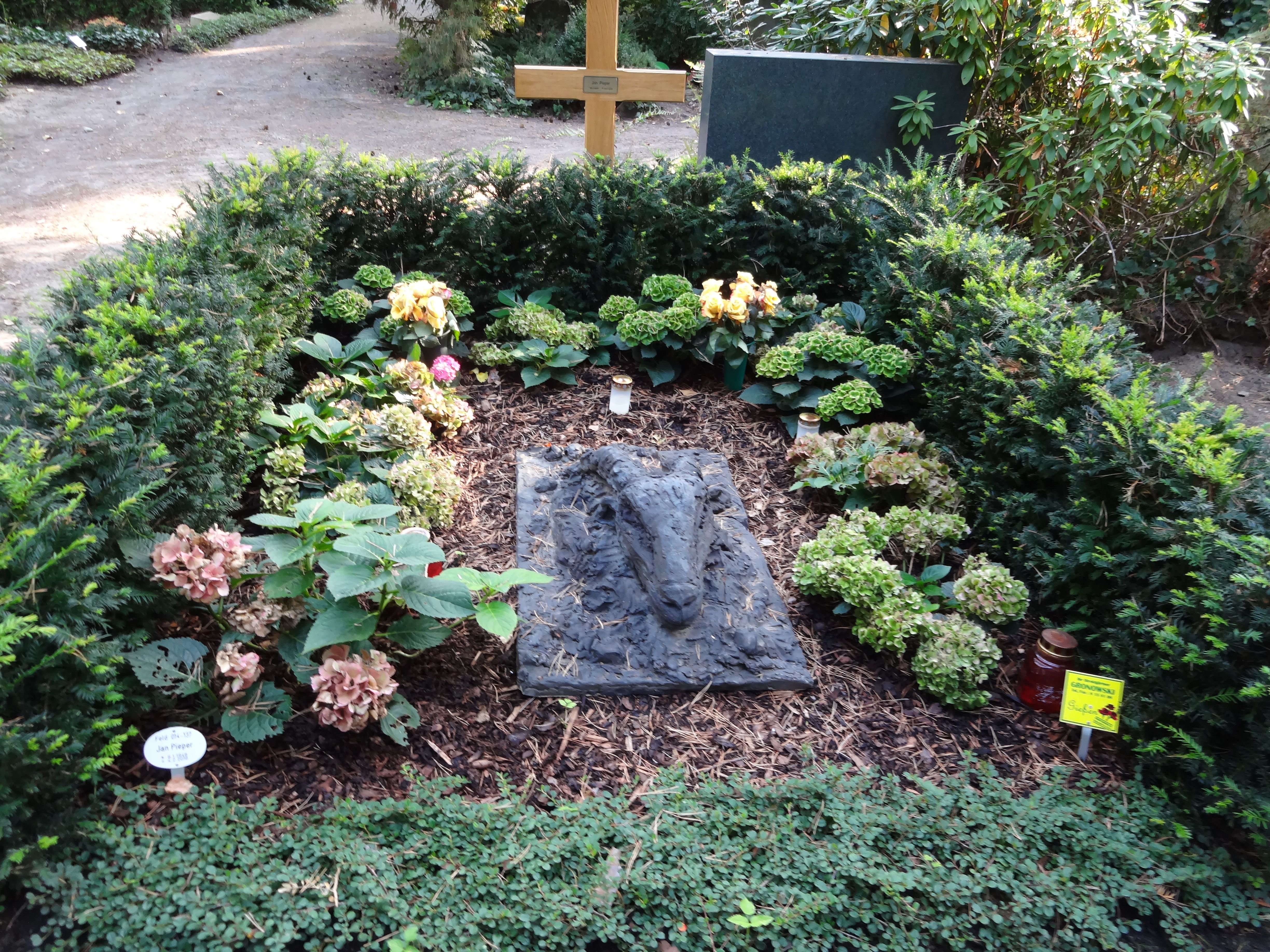 Bepflanzte Grabstätte mit liegender Schafskopf-Skulptur auf dem Waldfriedhof Dahlem